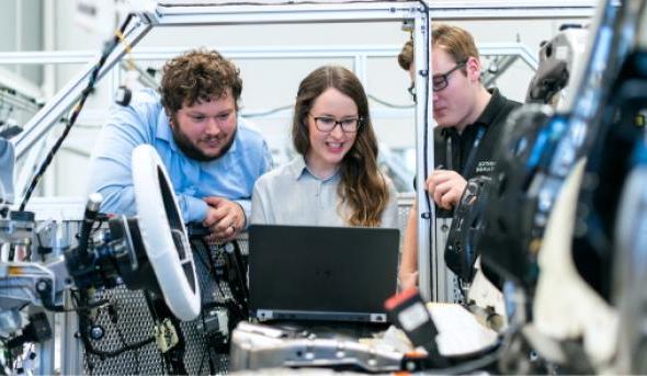 Three students working on a laptop